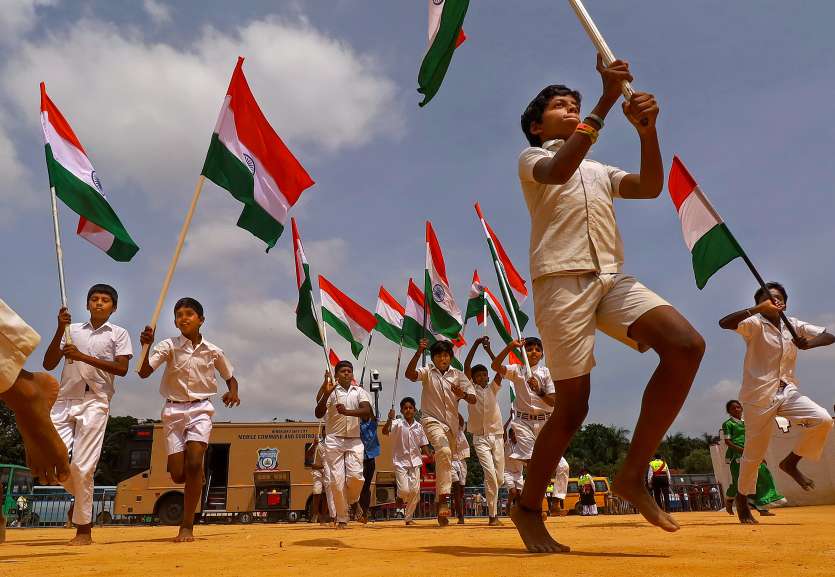 Children running with little flags of India in their hands.